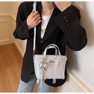 Detail of oil wax leather bucket bag with silver bow charm and lace ribbon decoration