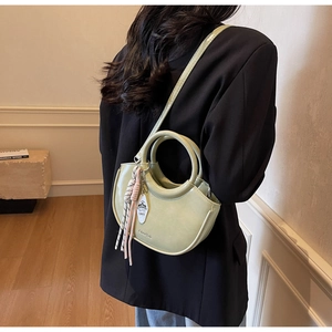 Detail of light green half-moon handbag with striped tassel and brand logo embossing