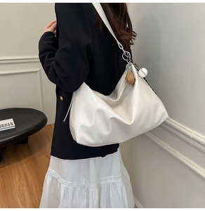 Detail of white glossy hobo bag with cute bear charm and wide shoulder strap