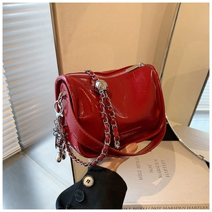Detail view of red glossy crossbody bag featuring silver chain strap and FASHION logo