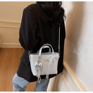 Detail of light blue bucket bag featuring white lace bow and silver heart pendant charm