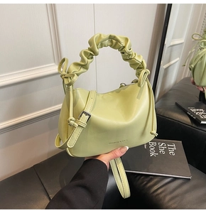Detail of light green PU leather bag with knotted handle and bow drawstring accents