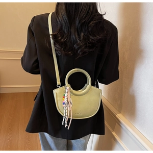Back view of a model wearing a light green crescent bucket bag with a round handle