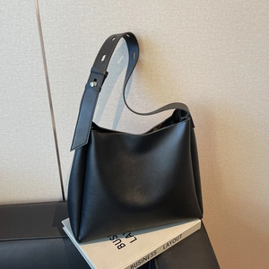 Detail of adjustable wide shoulder strap with silver buckle on black leather bucket bag