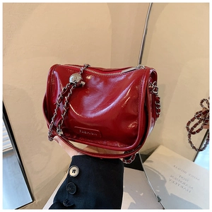 Close-up of red patent leather shoulder bag with silver hardware and fashion text