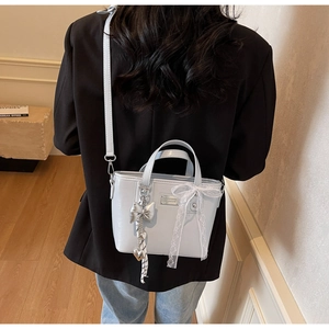 Detail of light blue glossy mini bucket bag with silver bow charm and lace ribbon