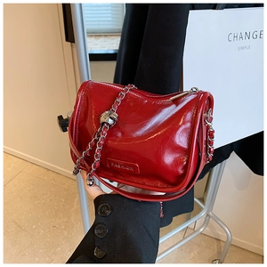 Close-up of shiny red pleated handbag with metal chain strap and silver ball charm