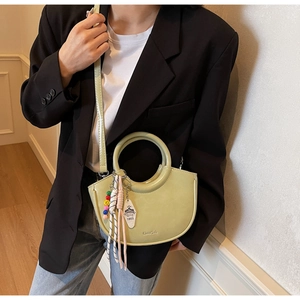 Detail of light green crescent handbag featuring a round handle and colorful bead charms