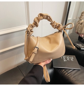 Detail of apricot large capacity bag with ruched handle and side tassel accents