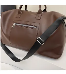 Détail d'un grand sac de voyage marron avec bandoulière lisse et poche zippée pratique