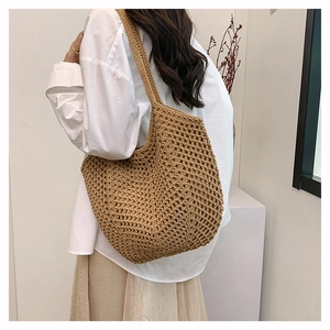 Detail of the woven texture and hollow crochet pattern on the light brown straw tote bag
