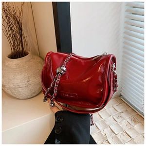 Detail of bright red patent leather handbag with silver chain strap and fashion logo