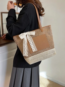 Sac cabas bicolore en paille avec nœud en dentelle et patch en cuir porté par un mannequin