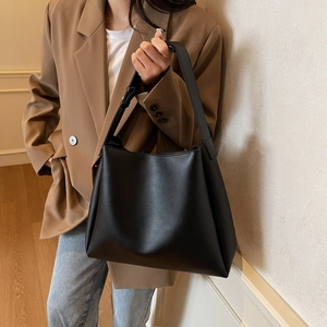Detail view of adjustable wide shoulder strap on a black minimalist leather bucket bag
