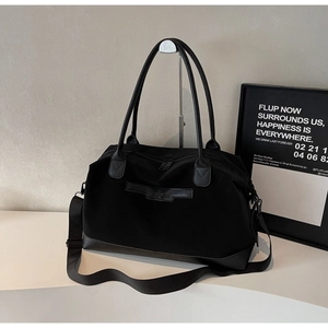 Détail du grand sac cabas noir avec fond en cuir et bandoulière en nylon réglable