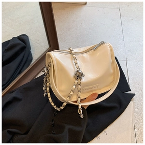 Detailed view of cream-colored leather handbag with metal chain and fashion engraving
