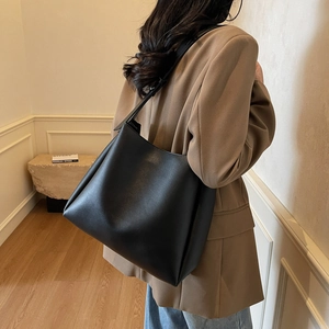 Minimalist black large hobo bag styled with a professional brown suit and denim