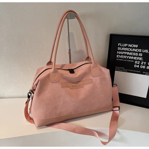 Détail macro du grand sac de voyage rose avec logo et poignée renforcée en cuir
