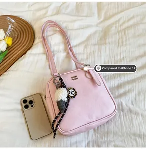 Pink faux leather shoulder bag next to iPhone 12 showing compact size and charm