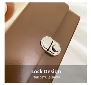 Close-up of a silver twist lock clasp on a brown leather crossbody box bag
