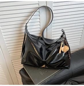 Detailed macro view of the glossy black tote bag with sports themed charms