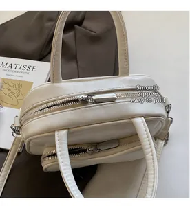 Close-up of smooth double silver zippers on a white leather Boston style handbag