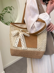 Sac fourre-tout en paille avec nœud en dentelle et anses en cuir porté par un mannequin