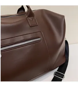 Détail du sac de voyage marron foncé en similicuir avec textures et fermetures éclair argentées