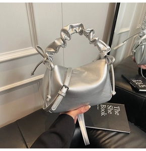 Close-up of metallic silver dumpling bag with ruffled handle and side bow detail