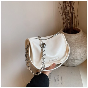 Detailed shot of cream PU leather handbag with silver chain strap and metal ball decoration