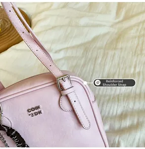Detail of pink leather handbag showing reinforced strap attachment and metal buckle