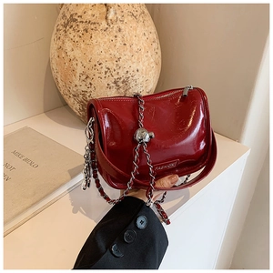 Close-up of deep red glossy leather handbag with silver chain and sphere detail