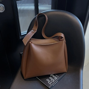 Close-up of brown faux leather tote bag with wide strap and silver buckle detail