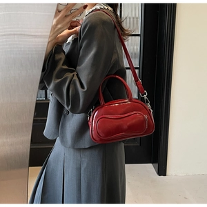 Détail macro du sac Boston en cuir verni rouge vin avec poche 3D distinctive