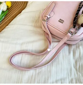 Detail of pink leather shoulder bag with NQE COIN logo and silver metal hardware