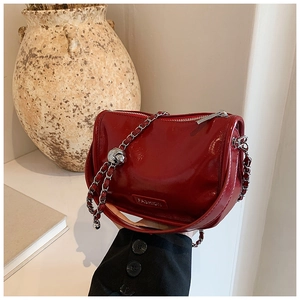 Close-up of dark red patent leather handbag with silver chain and sphere detail