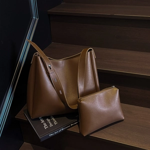 Detail view of deep brown bucket bag set with matching zipper pouch on wooden stairs