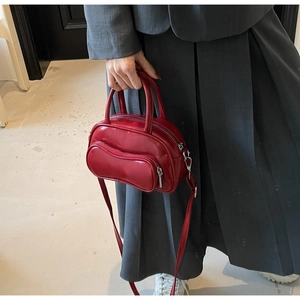 Sac Boston rouge brillant porté avec un blazer gris pour un look professionnel