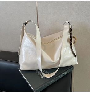 Macro shot of cream patent leather tote with glossy finish and baseball pendant detail