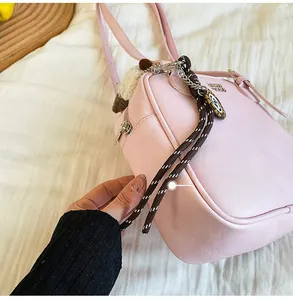 Side view of pink textured leather crossbody bag with braided rope and metal logo