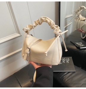 Detail of cream pleated handle bag featuring embossed fashion text and PU leather texture