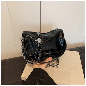 Detail of glossy patent leather texture and silver ball chain on black shoulder bag