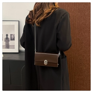 Detailed back view of a woman wearing a dark brown leather crossbody box bag with silver chain