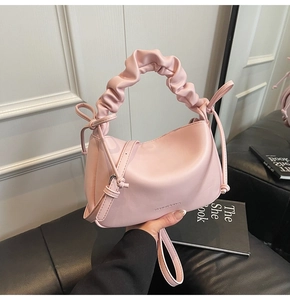 Detailed shot of pink pleated handle handbag with drawstring bows and logo lettering