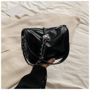 Detailed macro view of black glossy patent leather texture and silver chain strap
