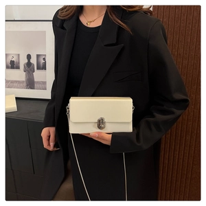 Chic cream small square bag with silver chain strap worn by a model in a black blazer