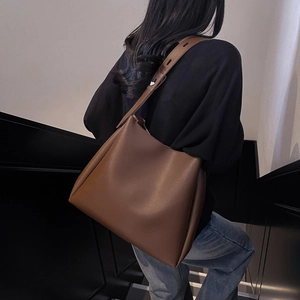 Detailed view of dark brown leather bucket bag with wide adjustable shoulder strap