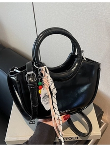 Black glossy crescent handbag with circular handles and decorative beaded charms