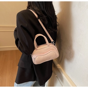 Détail du sac Boston rose brillant avec ferrures argentées et design ondulé