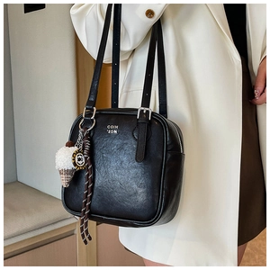 Detail of black faux leather shoulder bag featuring ice cream charm and logo print